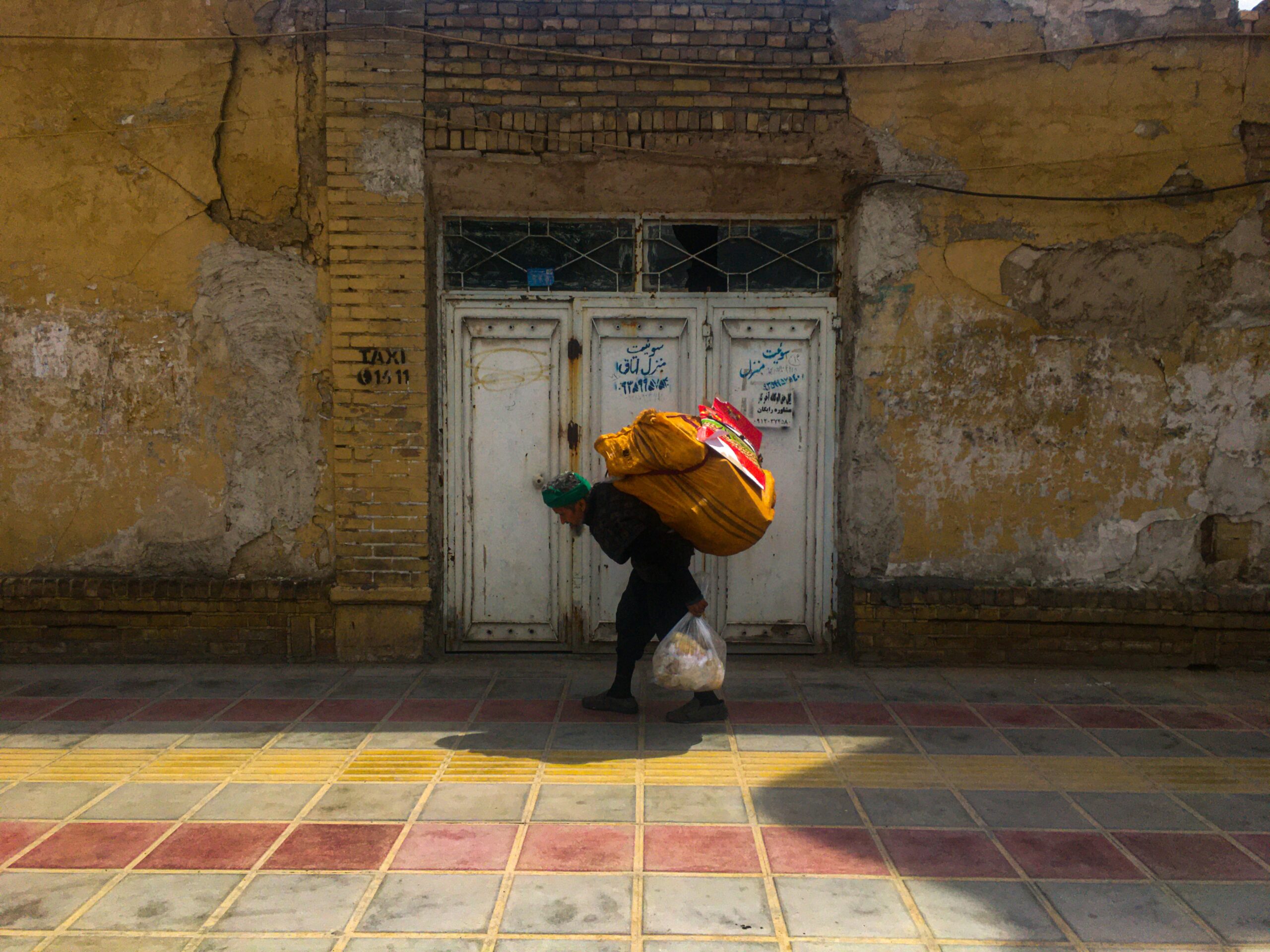 woman in black jacket and brown pants carrying red and yellow umbrella